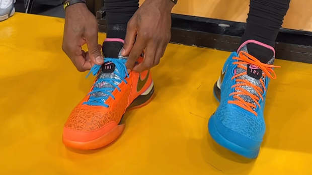 LeBron James ties his blue and orange shoes.